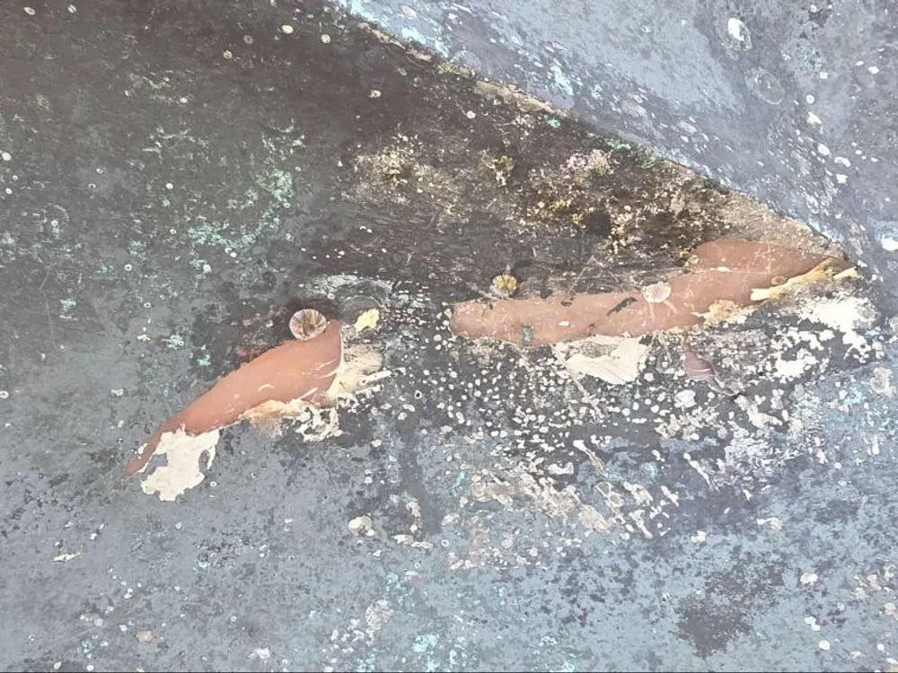 Crack in the underwater hull beneath the bow thruster, scraped open around it