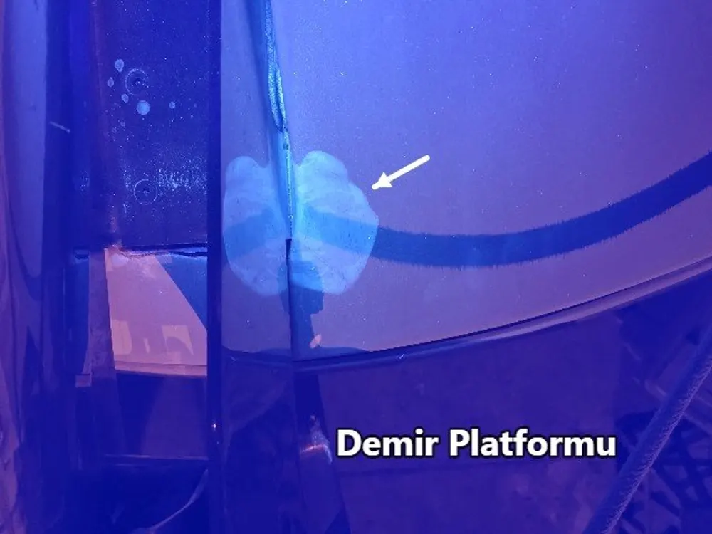 Paint and gelcoat repair showing on the hull under infrared light at night, marked with an arrow