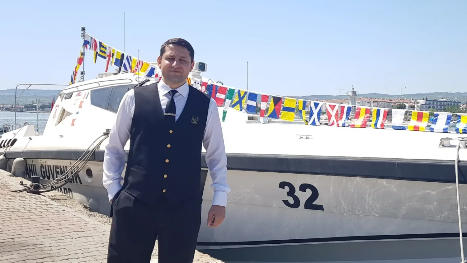 Serkan Kotel, bayraklarla donatılmış bir teknenin önünde